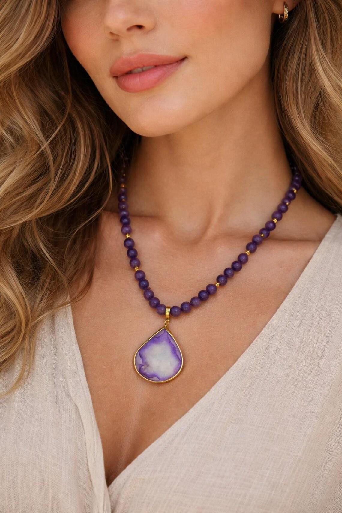 Amethyst and druzy agate pendant necklace worn around the neck.