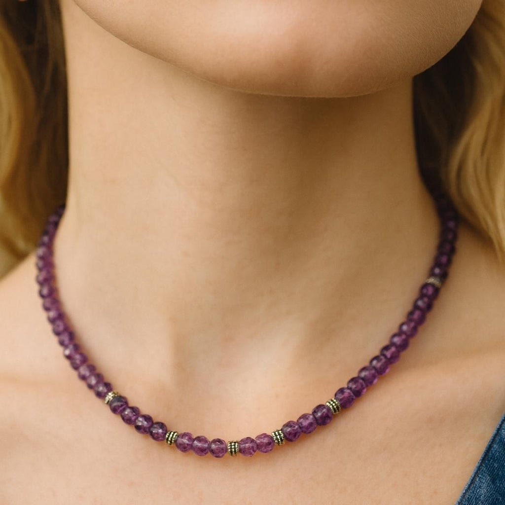 Amethyst bead necklace worn around the neck.