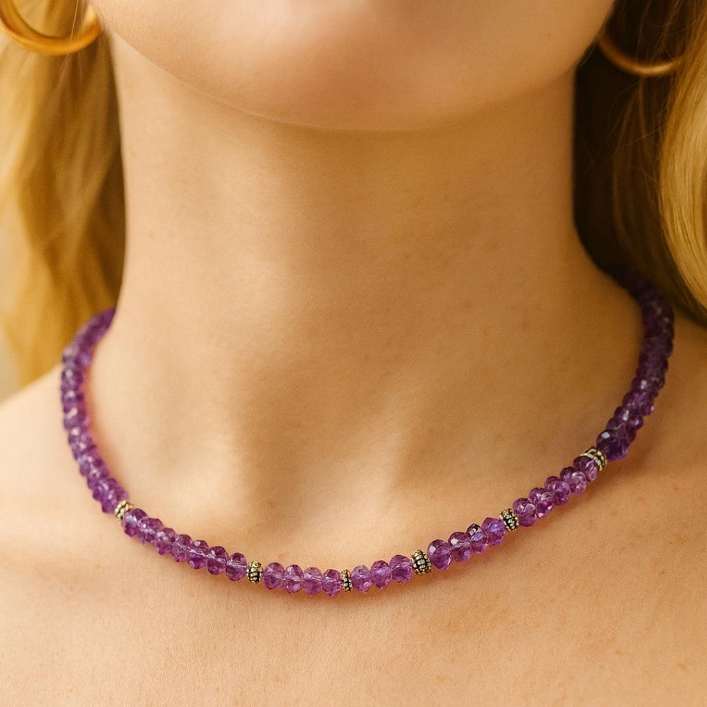 Amethyst bead necklace worn around the neck.