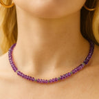 Amethyst bead necklace worn around the neck.