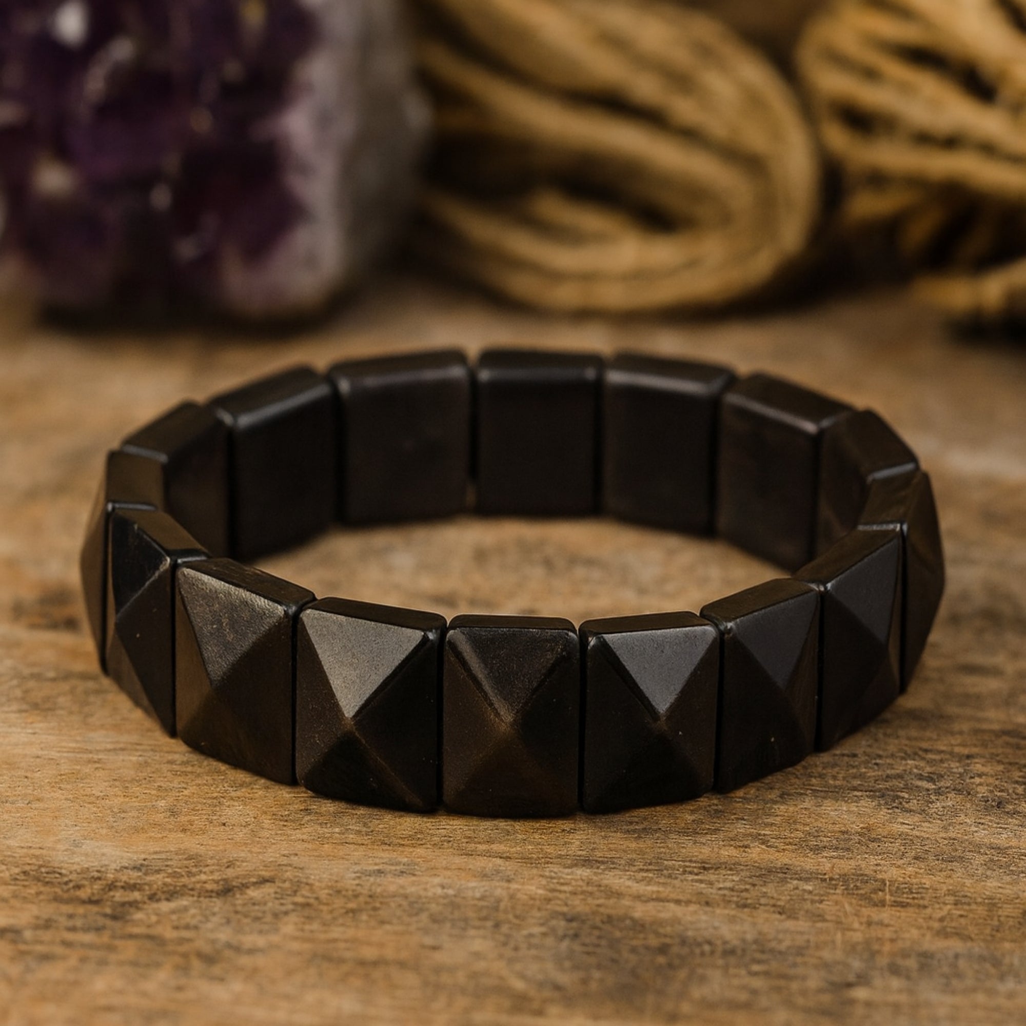 Silver Obsidian pyramid bracelet displayed on a warm wooden surface, highlighting its earthy grounding energy. Handcrafted 12x12mm cut stones connected on a flexible elastic band. Natural crystal jewelry for daily wear and spiritual practice. Obsidian protection bracelet, luxury gemstone gift, grounding talisman for men.
